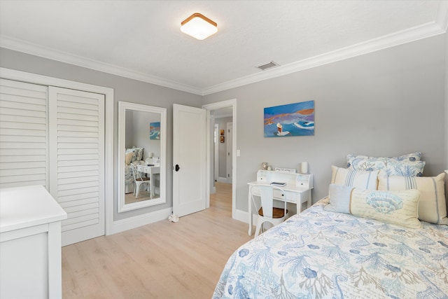 bedroom with visible vents, light wood-style flooring, a closet, crown molding, and baseboards