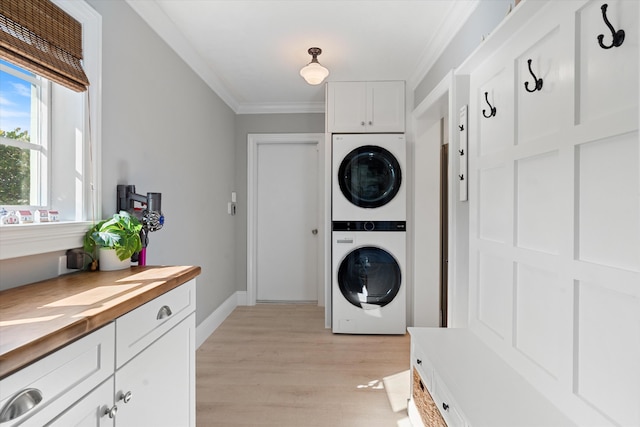 washroom with light wood finished floors, stacked washer / dryer, crown molding, and baseboards