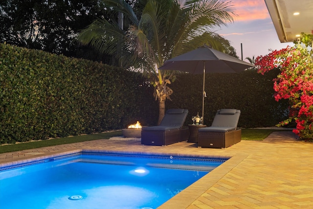 view of swimming pool featuring a fenced in pool, a fire pit, and a patio