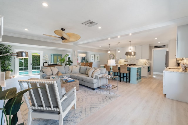 living room featuring light wood-type flooring, visible vents, ornamental molding, a ceiling fan, and recessed lighting