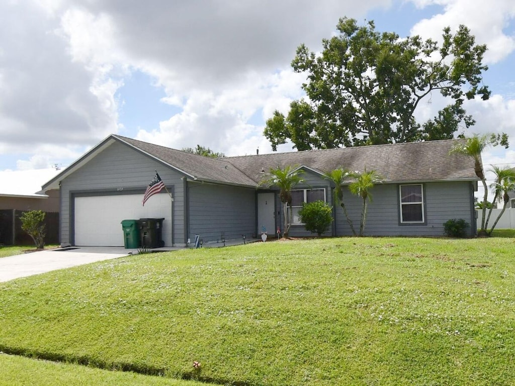 ranch-style house featuring a garage, concrete driveway, and a front lawn