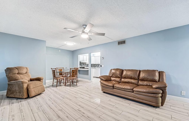 living area featuring baseboards, wood finish floors, visible vents, and a ceiling fan