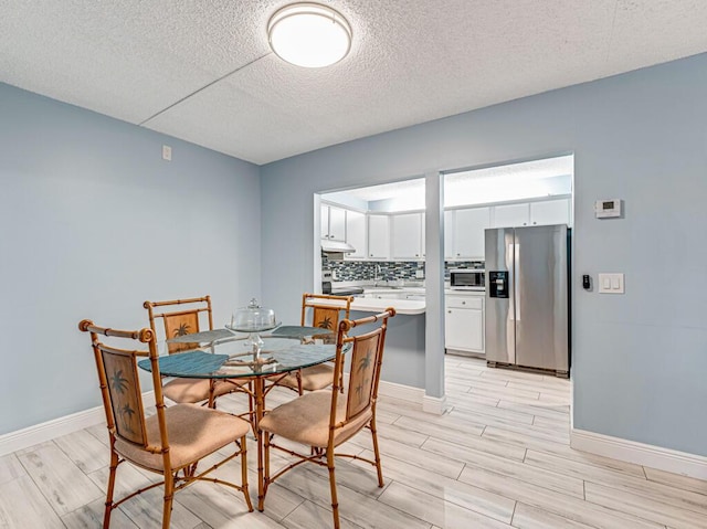 dining space with wood tiled floor, baseboards, and a textured ceiling