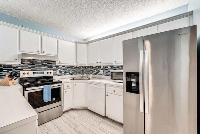 kitchen featuring appliances with stainless steel finishes, light countertops, a sink, and under cabinet range hood