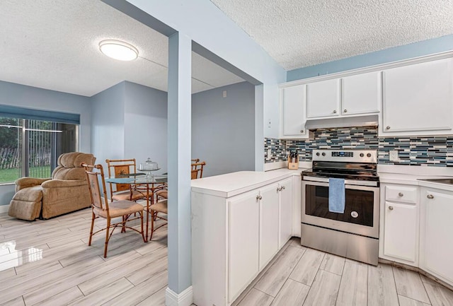 kitchen featuring light countertops, electric range, white cabinets, a peninsula, and under cabinet range hood