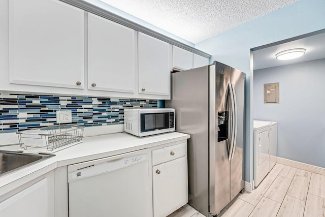 kitchen with white dishwasher, white cabinets, light countertops, independent washer and dryer, and stainless steel fridge with ice dispenser