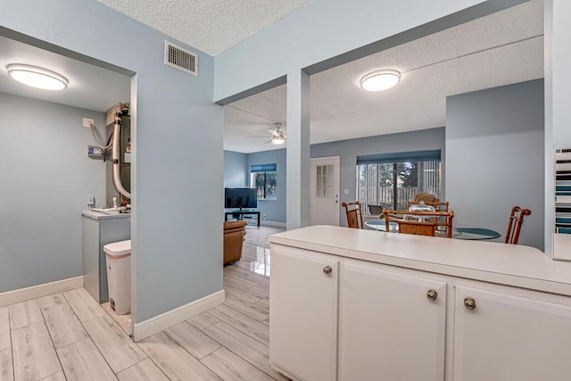 kitchen with white cabinetry, visible vents, light countertops, and wood finish floors