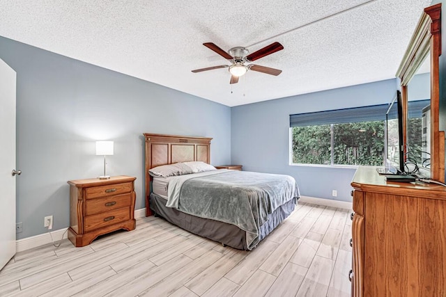 bedroom with wood tiled floor, baseboards, ceiling fan, and a textured ceiling