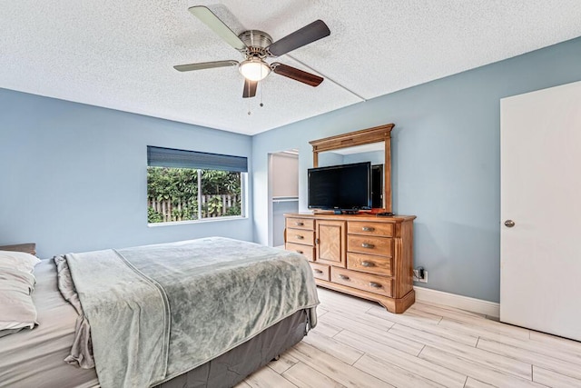 bedroom with a ceiling fan, wood tiled floor, baseboards, and a textured ceiling