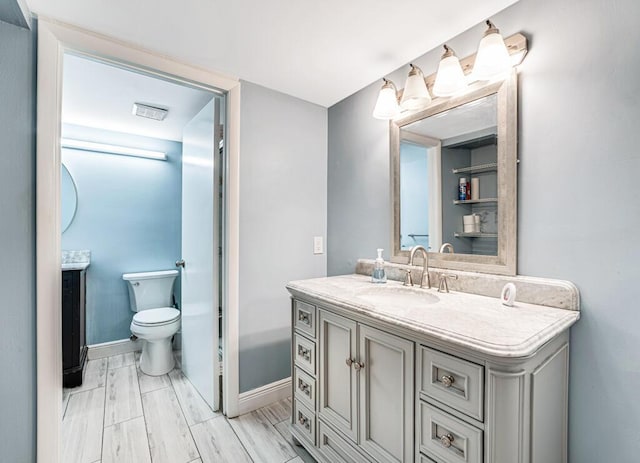 bathroom with baseboards, vanity, and toilet