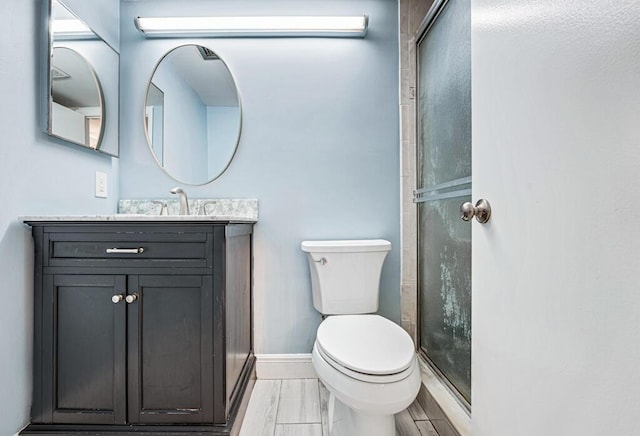 full bath with toilet, an enclosed shower, baseboards, and vanity