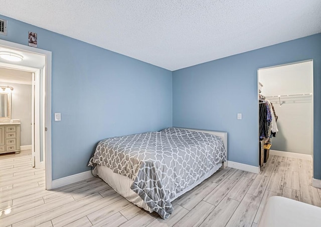 bedroom with baseboards, a spacious closet, a closet, and wood tiled floor