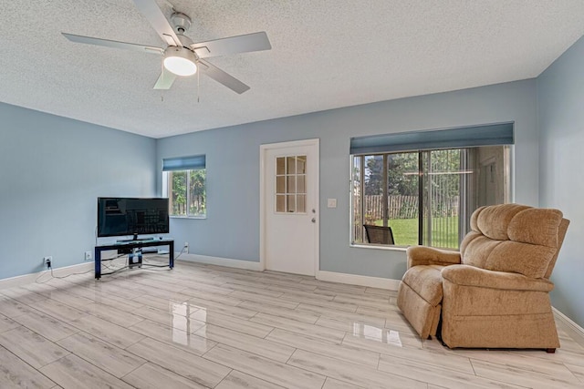 living area featuring wood tiled floor, a textured ceiling, and baseboards