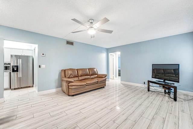 living room with baseboards, wood tiled floor, visible vents, and a ceiling fan