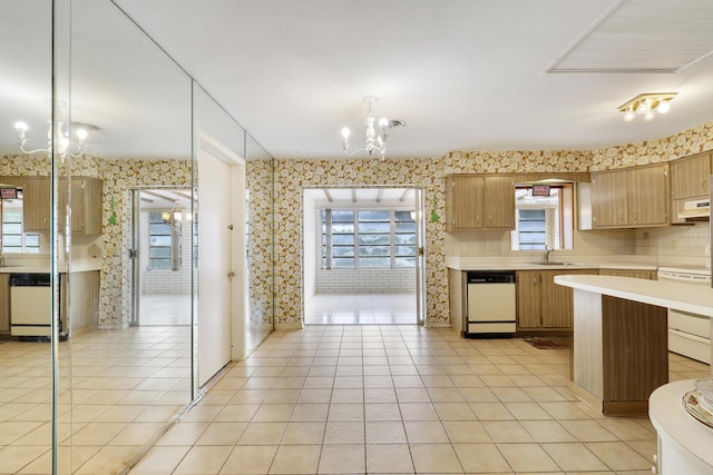 kitchen featuring range, white dishwasher, light countertops, and a notable chandelier