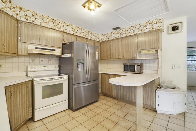 kitchen with under cabinet range hood, stainless steel appliances, visible vents, light countertops, and backsplash