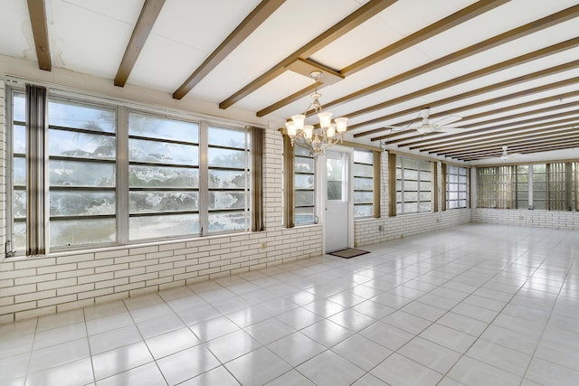 unfurnished room featuring a sunroom, brick wall, beamed ceiling, an inviting chandelier, and light tile patterned flooring