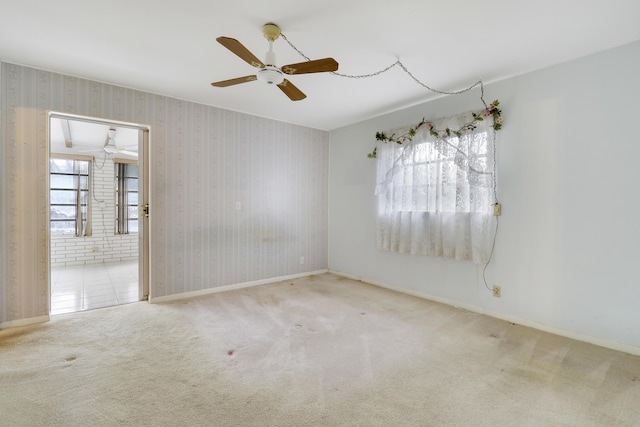 empty room with light carpet, wallpapered walls, baseboards, and a ceiling fan