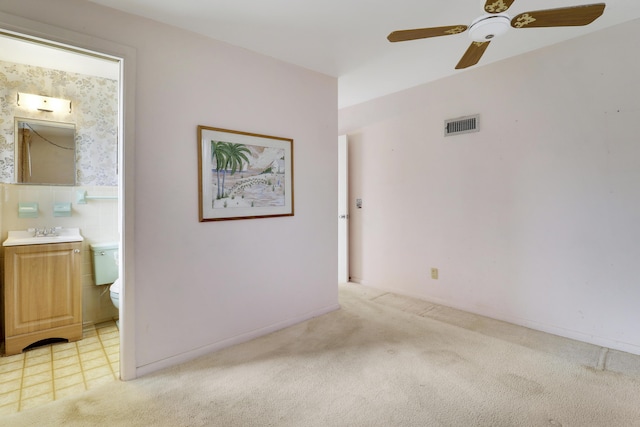 spare room with a ceiling fan, visible vents, a sink, and light colored carpet