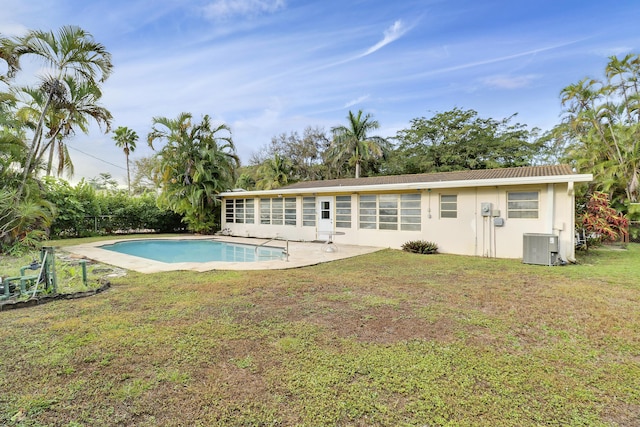 rear view of house featuring a patio, central air condition unit, an outdoor pool, a yard, and stucco siding