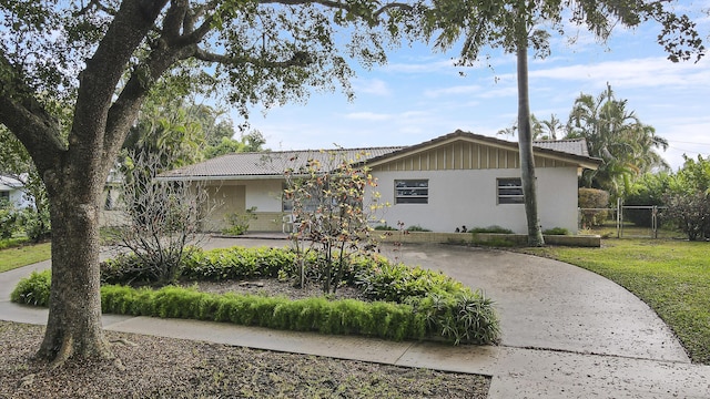 ranch-style home with driveway, a tile roof, fence, a front lawn, and stucco siding