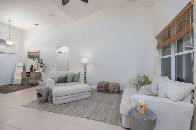 living room featuring visible vents, arched walkways, tile patterned floors, high vaulted ceiling, and a ceiling fan