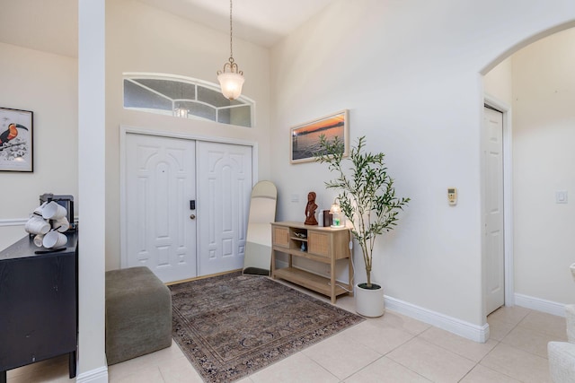 foyer entrance with light tile patterned floors, baseboards, and arched walkways