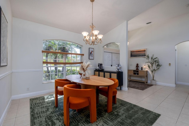 dining space with lofted ceiling, light tile patterned floors, baseboards, and arched walkways