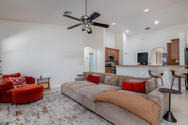 living area with arched walkways, visible vents, high vaulted ceiling, and ceiling fan