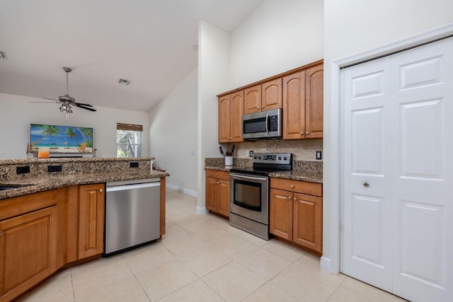 kitchen with visible vents, brown cabinets, stainless steel appliances, and dark stone counters