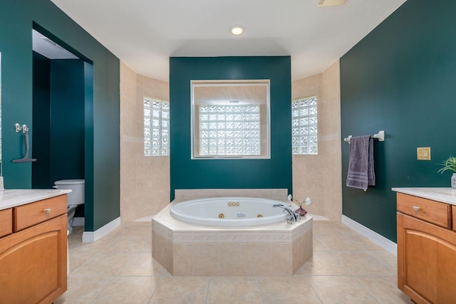 bathroom with tile patterned floors, toilet, vanity, baseboards, and a whirlpool tub