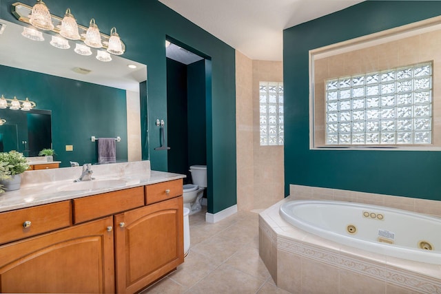 full bathroom with toilet, a whirlpool tub, tile patterned flooring, baseboards, and vanity