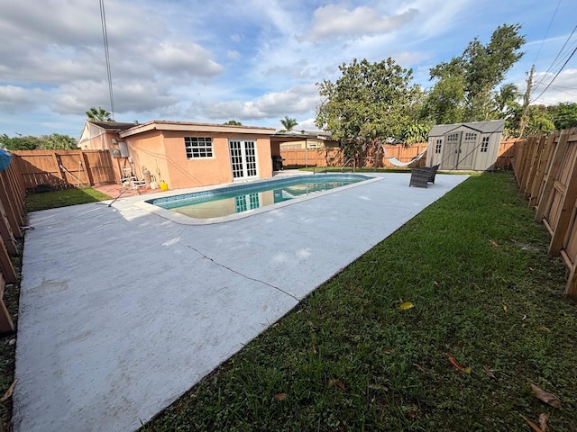 view of pool with a yard, a fenced backyard, a storage unit, and an outdoor structure