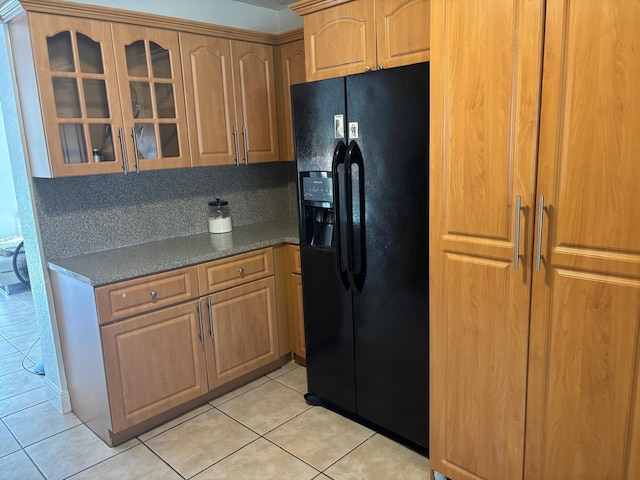 7430 Atlanta St, Hollywood, FL 33024 - kitchen with light tile patterned flooring, brown cabinets, black refrigerator with ice dispenser, dark countertops, and glass insert cabinets