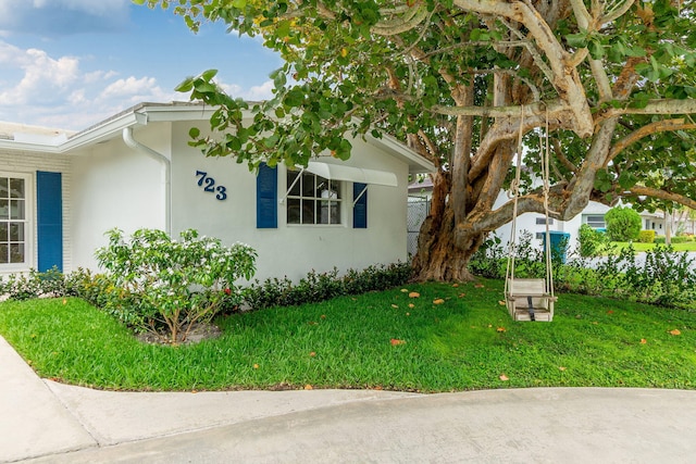 view of side of property with stucco siding and a lawn