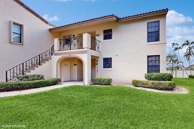 mediterranean / spanish-style house with a balcony, stairs, fence, a front lawn, and stucco siding