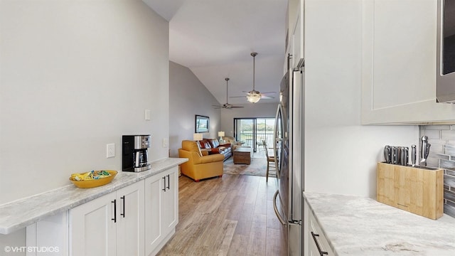 interior space with light wood-style floors, freestanding refrigerator, white cabinets, and open floor plan