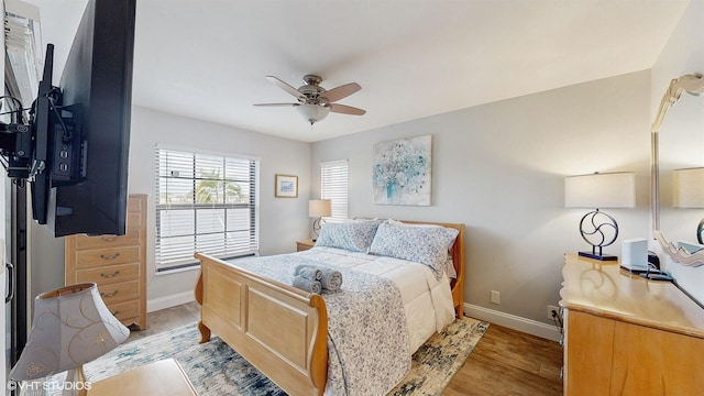 bedroom with light wood finished floors, baseboards, and a ceiling fan