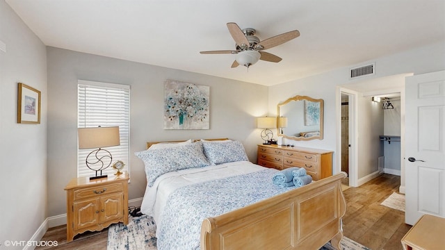 bedroom featuring a spacious closet, light wood finished floors, visible vents, and baseboards