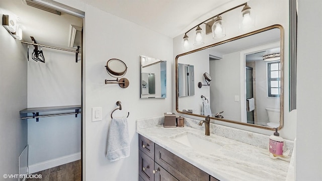 full bath featuring wood finished floors, vanity, toilet, and baseboards