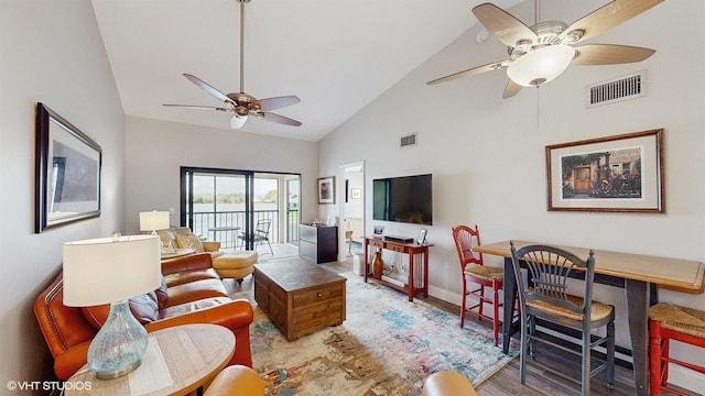 living area featuring high vaulted ceiling, light wood-style flooring, visible vents, baseboards, and a ceiling fan