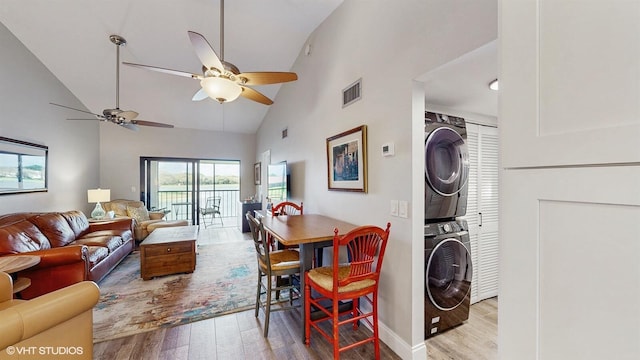 living room featuring high vaulted ceiling, light wood-type flooring, visible vents, and stacked washing maching and dryer