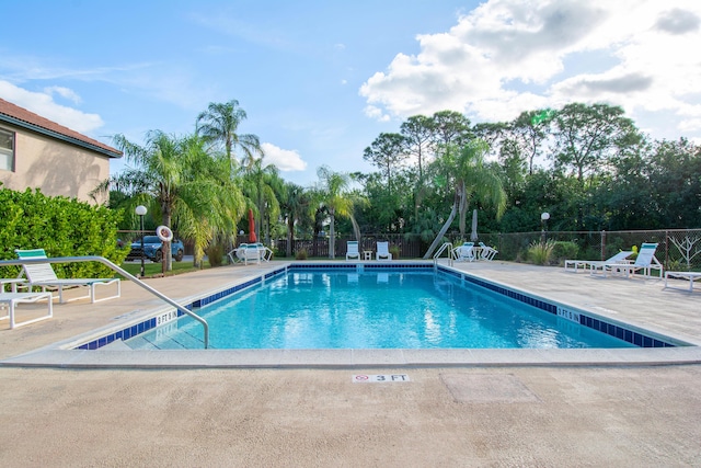 community pool with a patio and fence