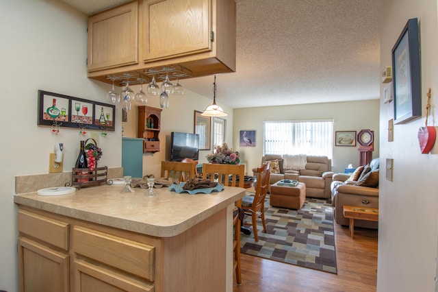 kitchen with a textured ceiling, light brown cabinets, light wood-style floors, open floor plan, and light countertops