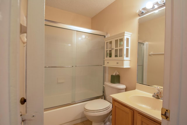 bathroom featuring a textured ceiling, combined bath / shower with glass door, vanity, and toilet