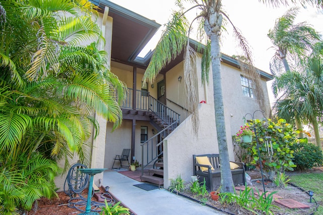 view of property exterior with stucco siding, a patio, and stairs