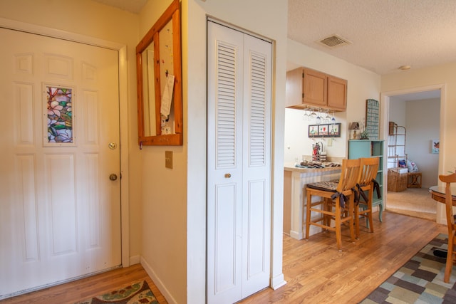 kitchen featuring baseboards, light wood-style flooring, visible vents, and a textured ceiling