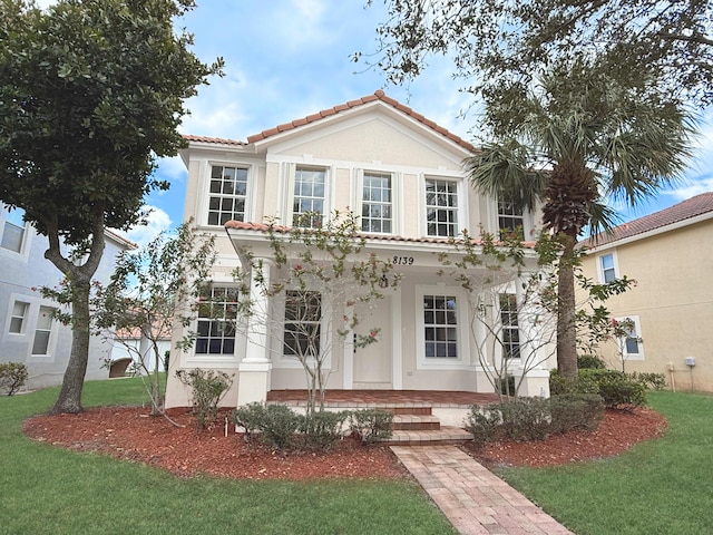 mediterranean / spanish-style house with a tiled roof, a front lawn, and stucco siding