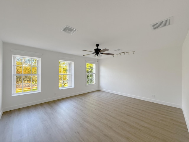 spare room featuring light wood finished floors, baseboards, and visible vents