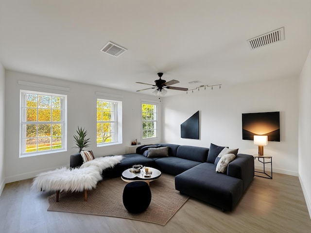 living room featuring visible vents, light wood-style flooring, and baseboards